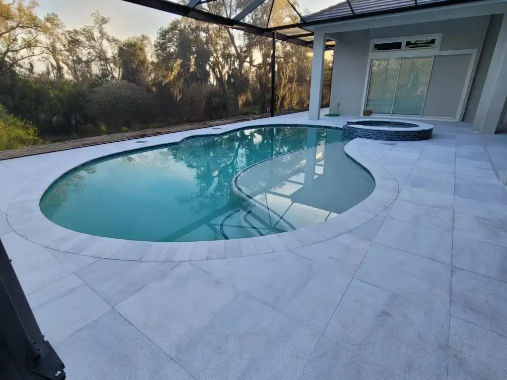 There is a large swimming pool in the backyard of a house