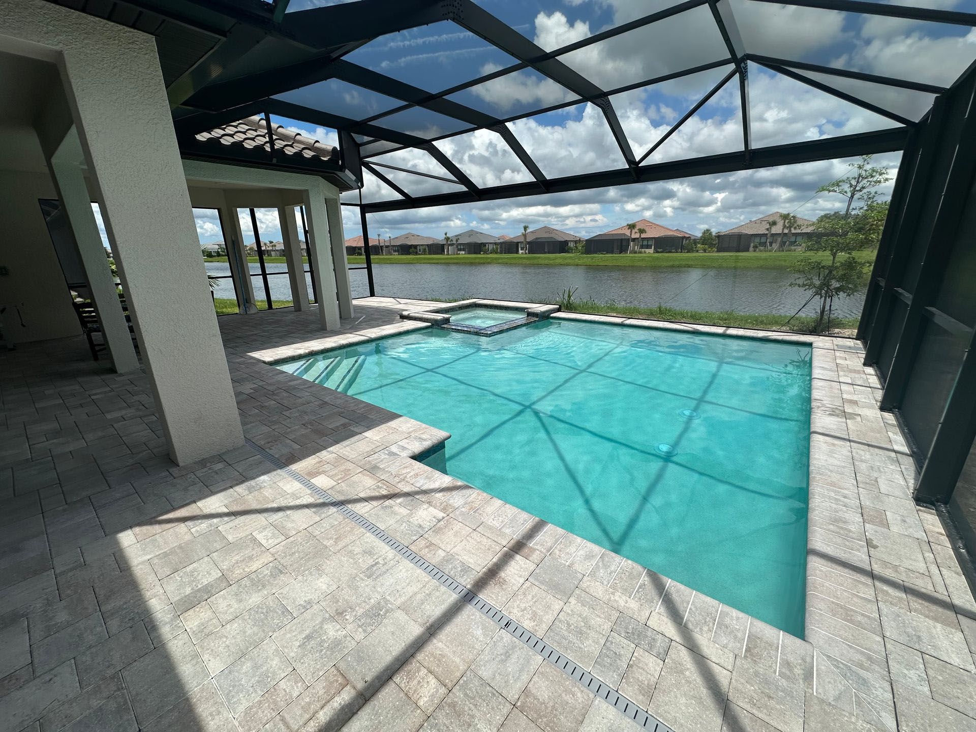 A large swimming pool is surrounded by a screened in area.