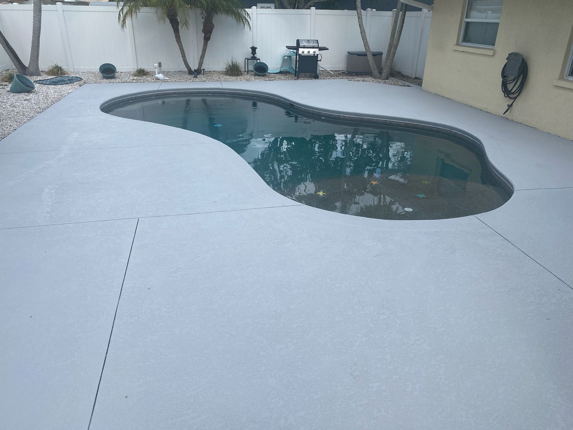 A swimming pool in a backyard with a concrete deck.
