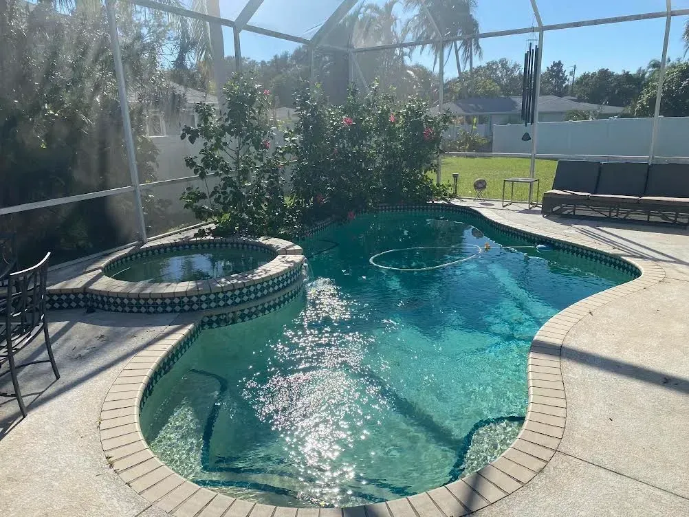 A large swimming pool with a hot tub in the middle