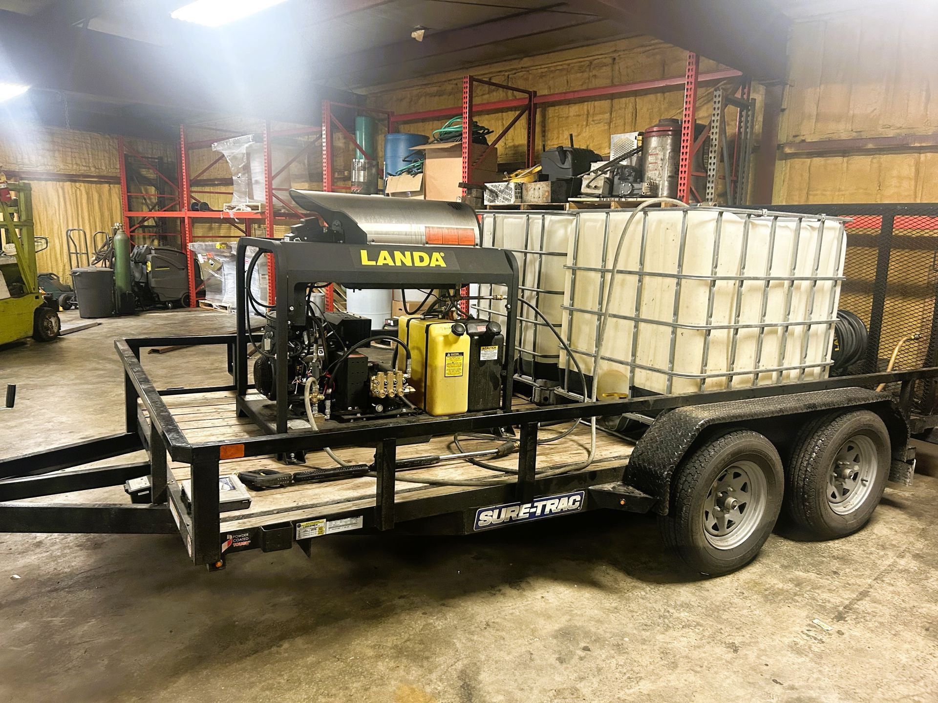 A trailer with a machine on it is parked in a garage.