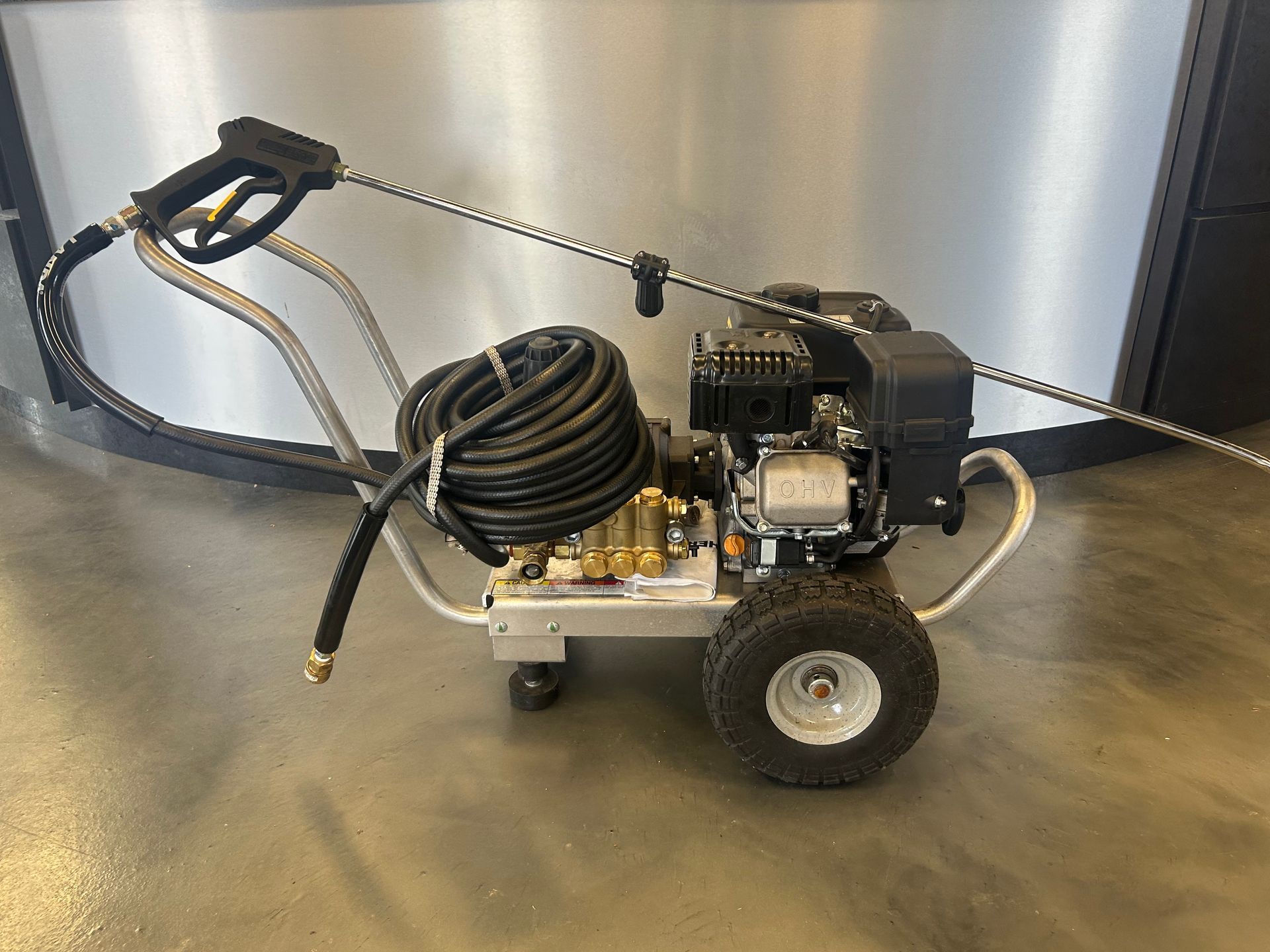 A high pressure washer with a hose attached to it is sitting on the floor.