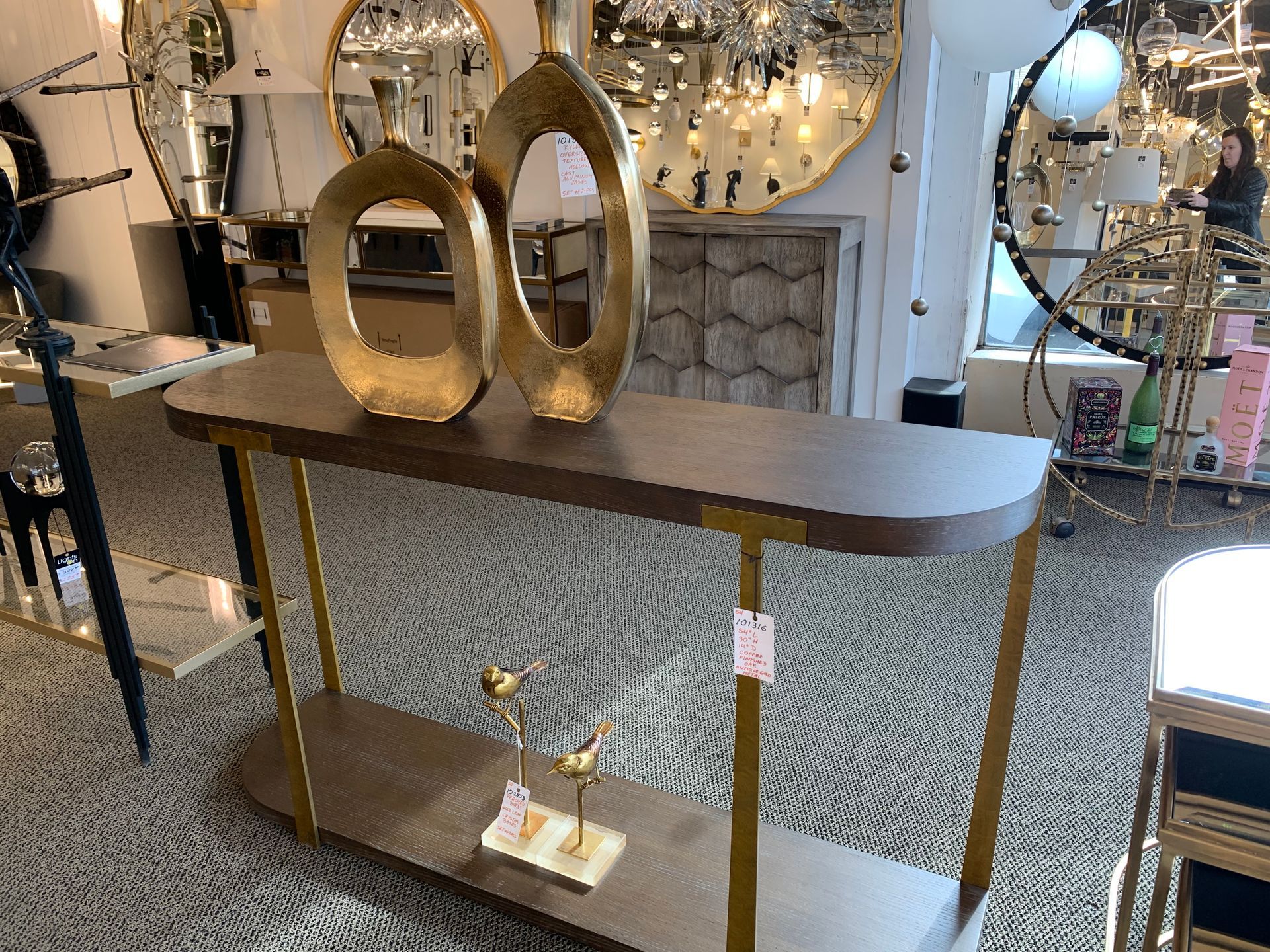 A wooden table with two gold vases on top of it in a room.
