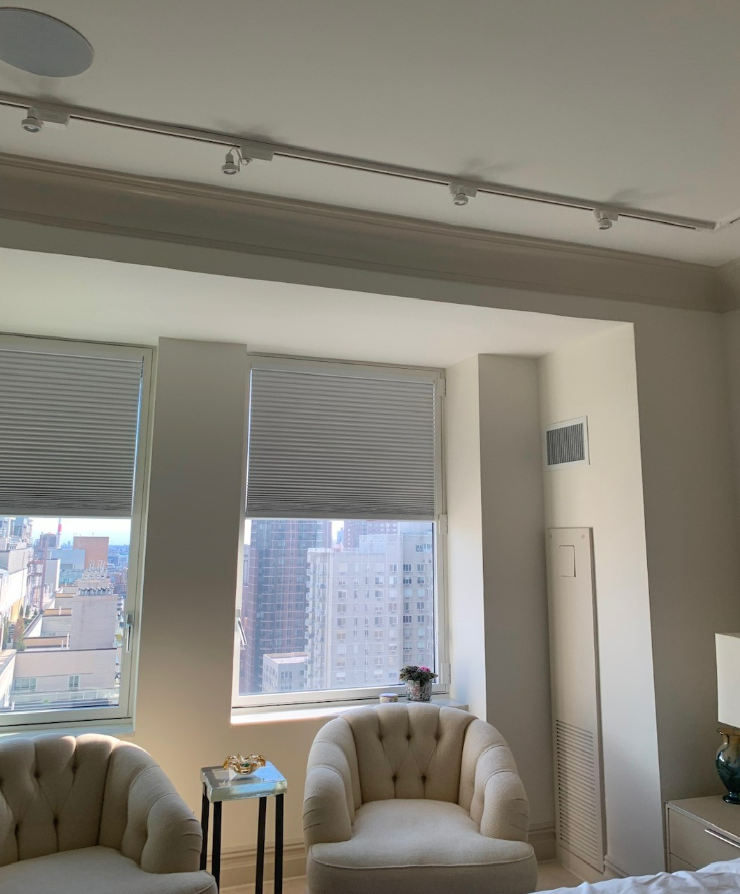 A bedroom with two chairs and a large window.