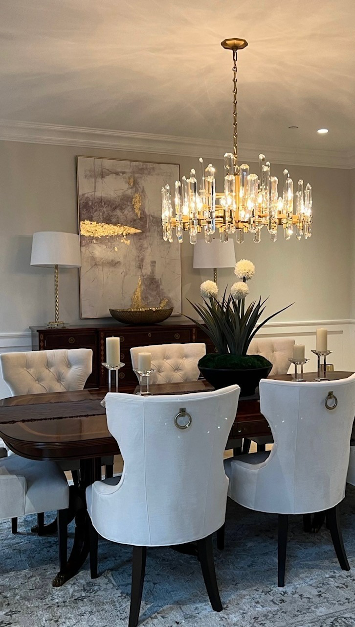 A dining room with a table and chairs and a chandelier hanging from the ceiling.