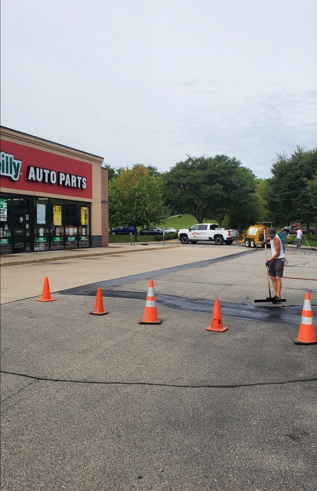 A man is standing in a parking lot in front of an auto parts store.