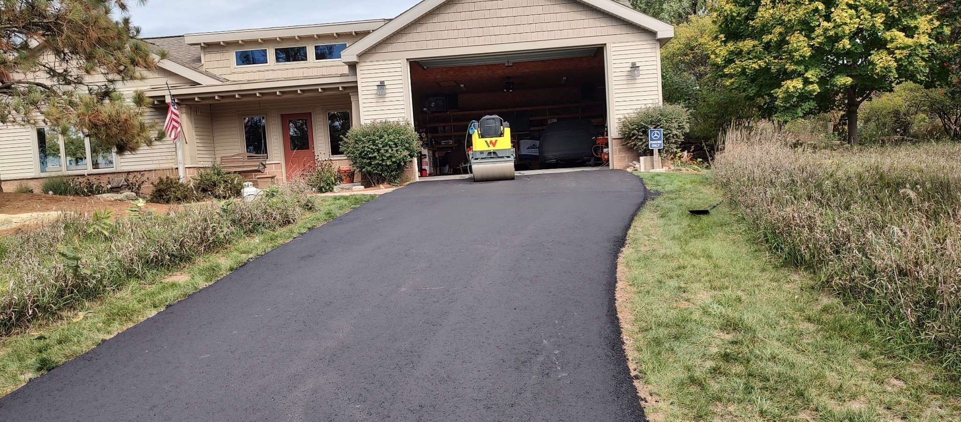 A driveway leading to a house with a car parked in the garage.