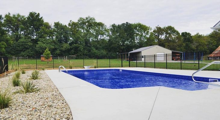 A large swimming pool surrounded by a fence in a backyard.