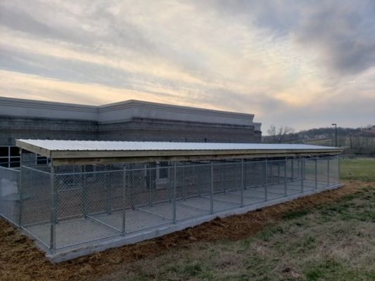 A fenced in area in front of a building with a roof.