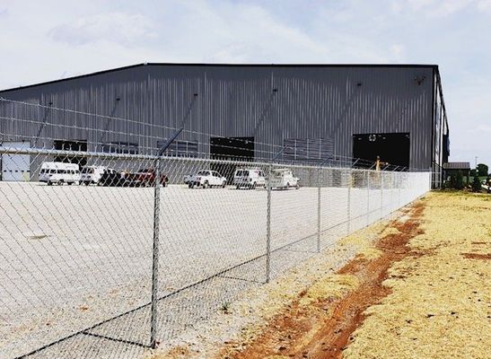 A chain link fence is surrounding a large building.