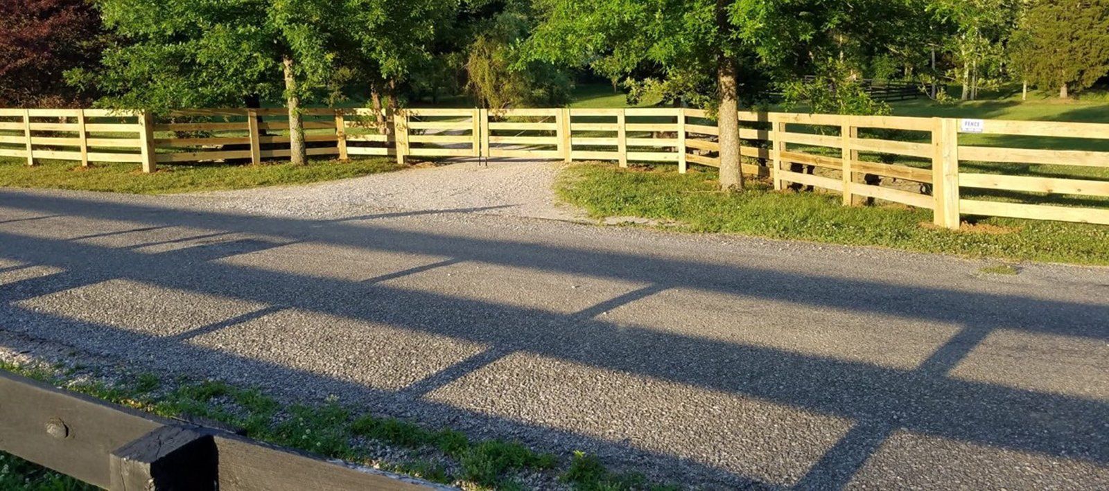 A wooden fence along the side of a gravel road.