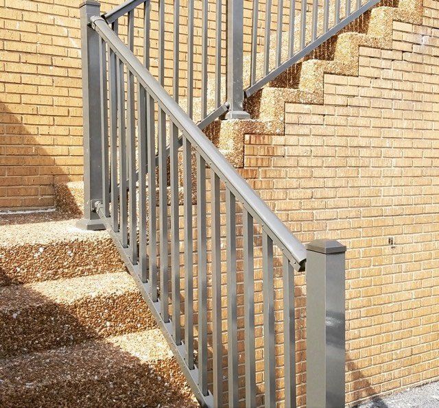 A set of stairs with a metal railing in front of a brick wall