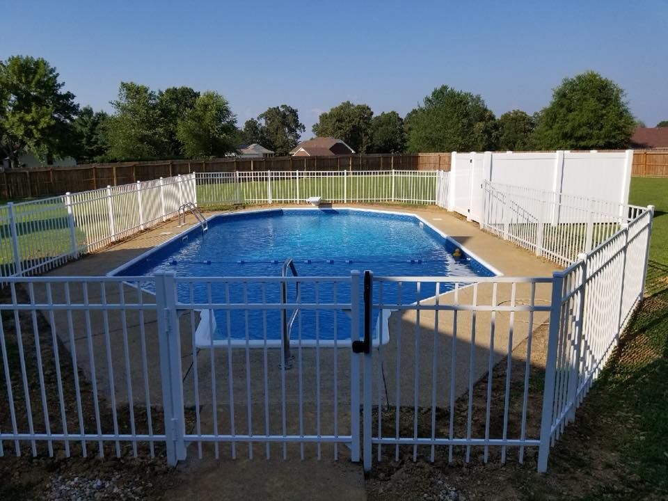 A large swimming pool with a white fence around it
