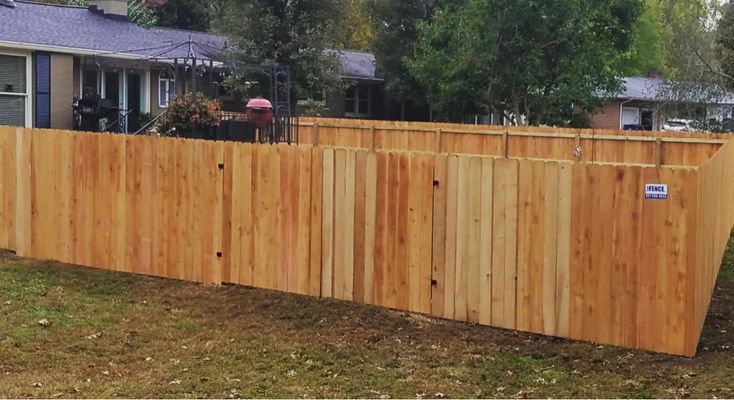 A wooden fence is sitting in the grass in front of a house.