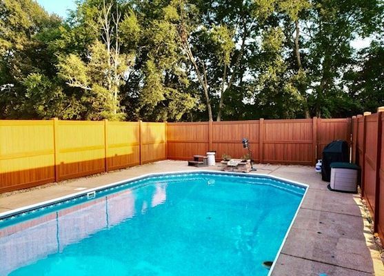A large swimming pool with a wooden fence surrounding it.