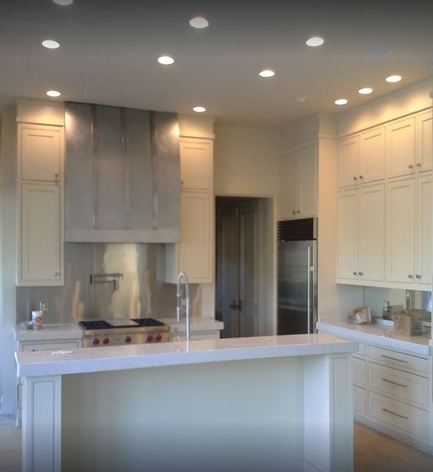 Modern kitchen with white cabinets, stainless steel range hood, and island.