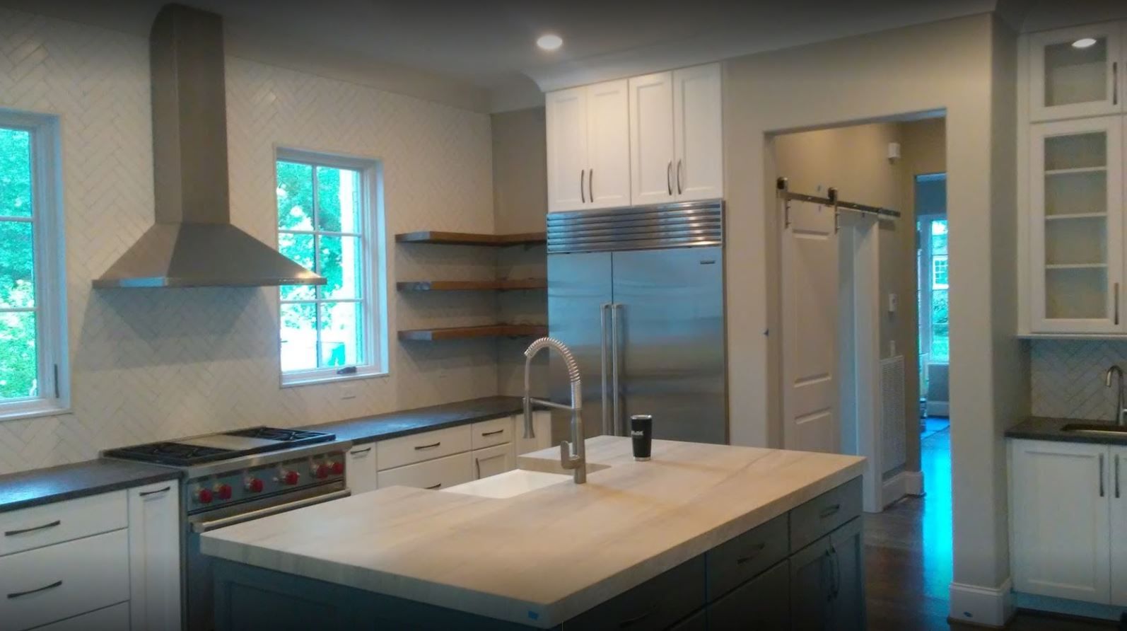 Modern kitchen with white cabinetry, stainless steel appliances, and a large island.