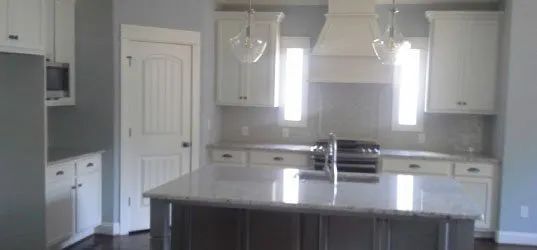 Modern kitchen with white cabinets, gray walls, and a large island.