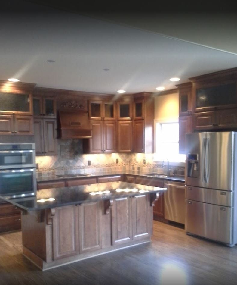 Kitchen with wooden cabinets, island, stainless steel appliances, and dark countertops.