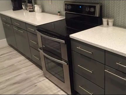 Modern kitchen with gray cabinets, white countertops, and stainless steel double oven.