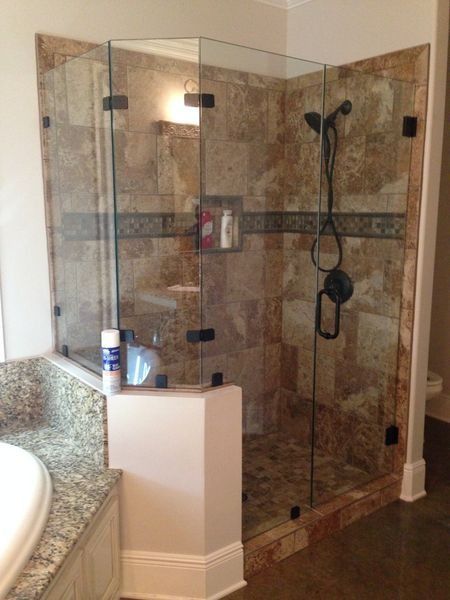 Glass shower enclosure with brown tile walls, black fixtures, and a corner design.