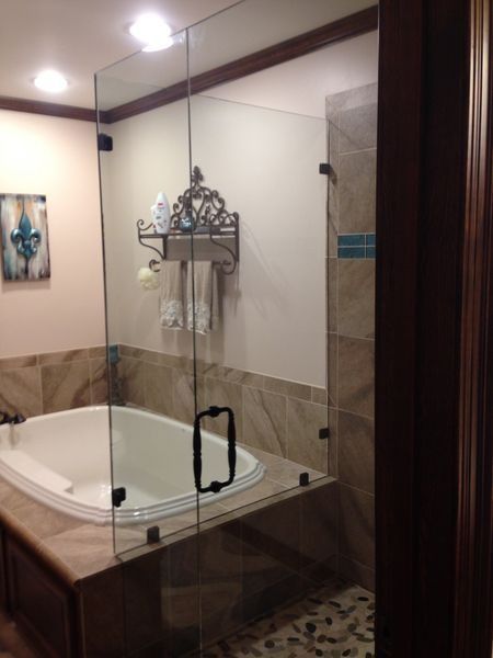Bathroom with a glass shower, beige tile, and a white oval tub.