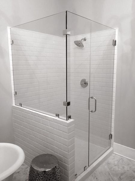 Glass shower enclosure with white brick walls, a door, and a showerhead.