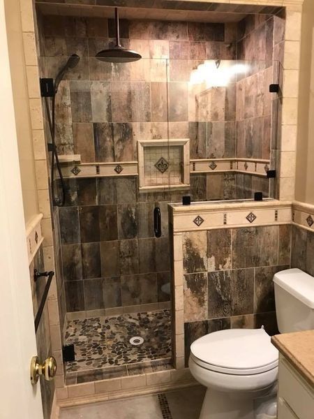 Bathroom with shower and toilet. Brown, beige tile. Glass shower door.
