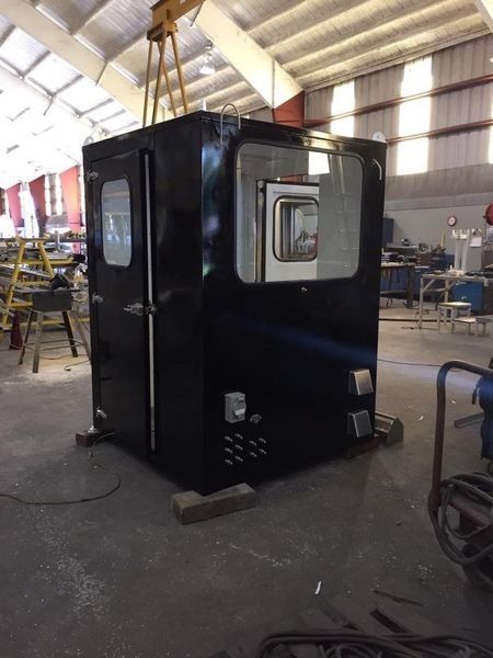 Black industrial booth with windows in a workshop.