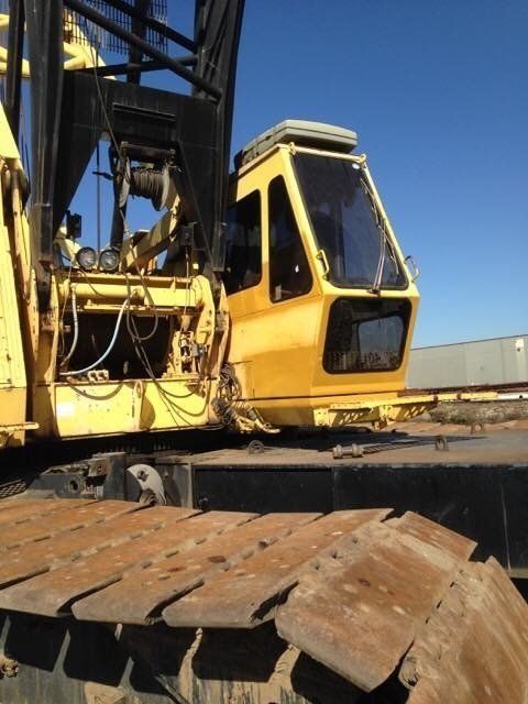Yellow construction crane with black details and operator cab, sitting outdoors.
