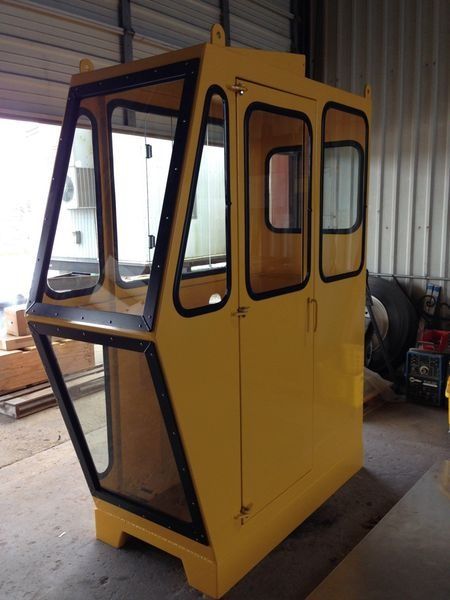 Yellow industrial crane cab with black window trim, ready for installation.