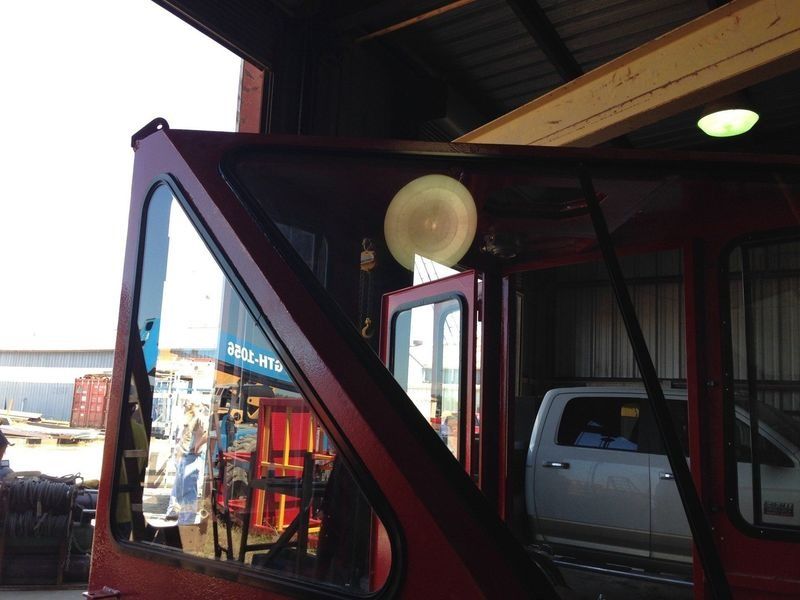 Red forklift cab with angled windows, a spotlight, parked in a warehouse.