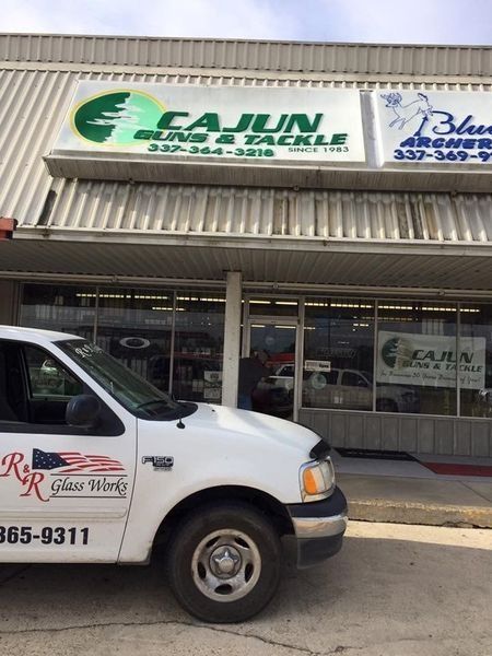 Cajun Guns & Tackle store with a white truck parked in front. The store has green signage.