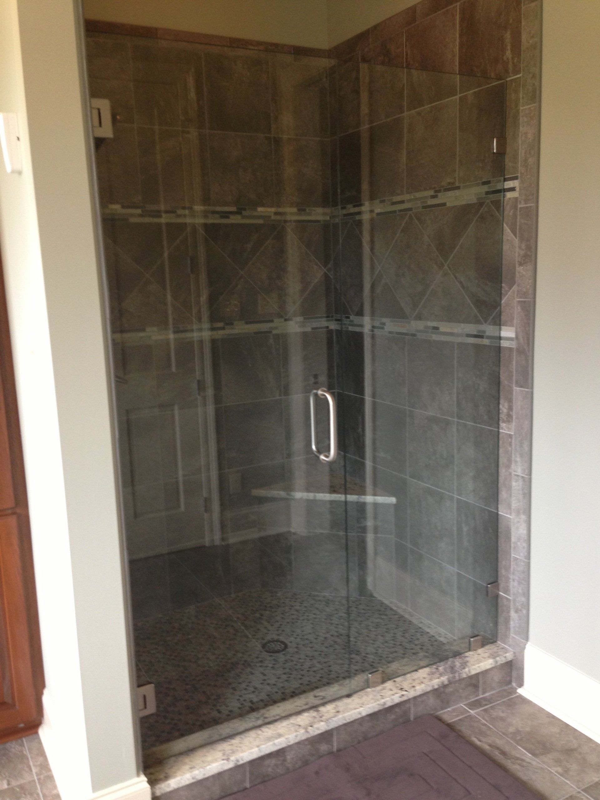 Glass shower enclosure with dark tile walls and pebble floor.
