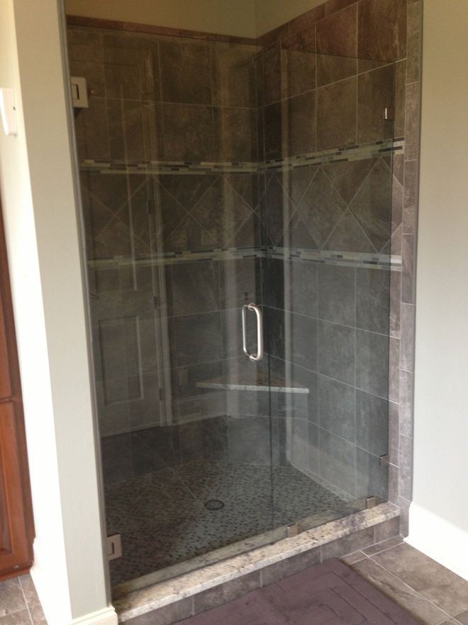 Glass shower enclosure with dark tile walls and pebble floor.