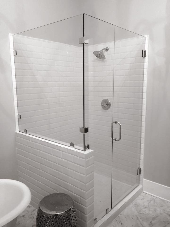 Glass shower enclosure with white subway tile, chrome fixtures, and a small stool.