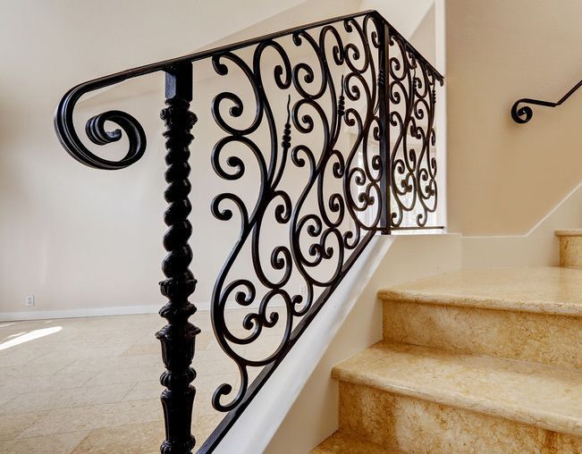 A close up of a wrought iron railing on a set of stairs