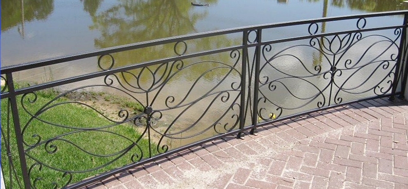 A wrought iron railing overlooking a body of water.