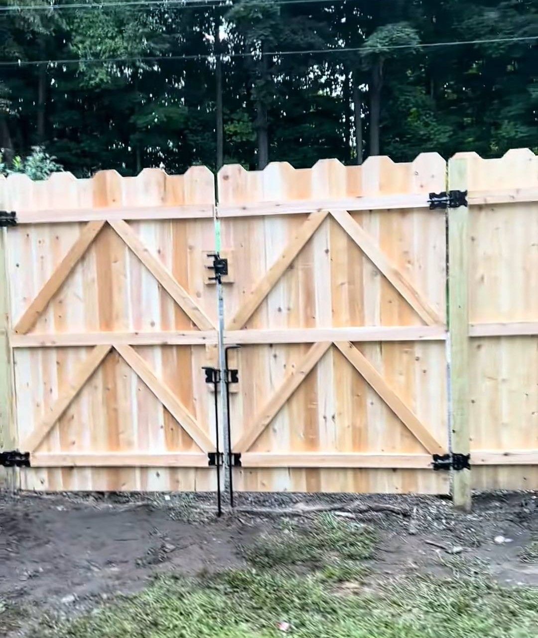 Wooden gate with triangular braces, between fence posts.