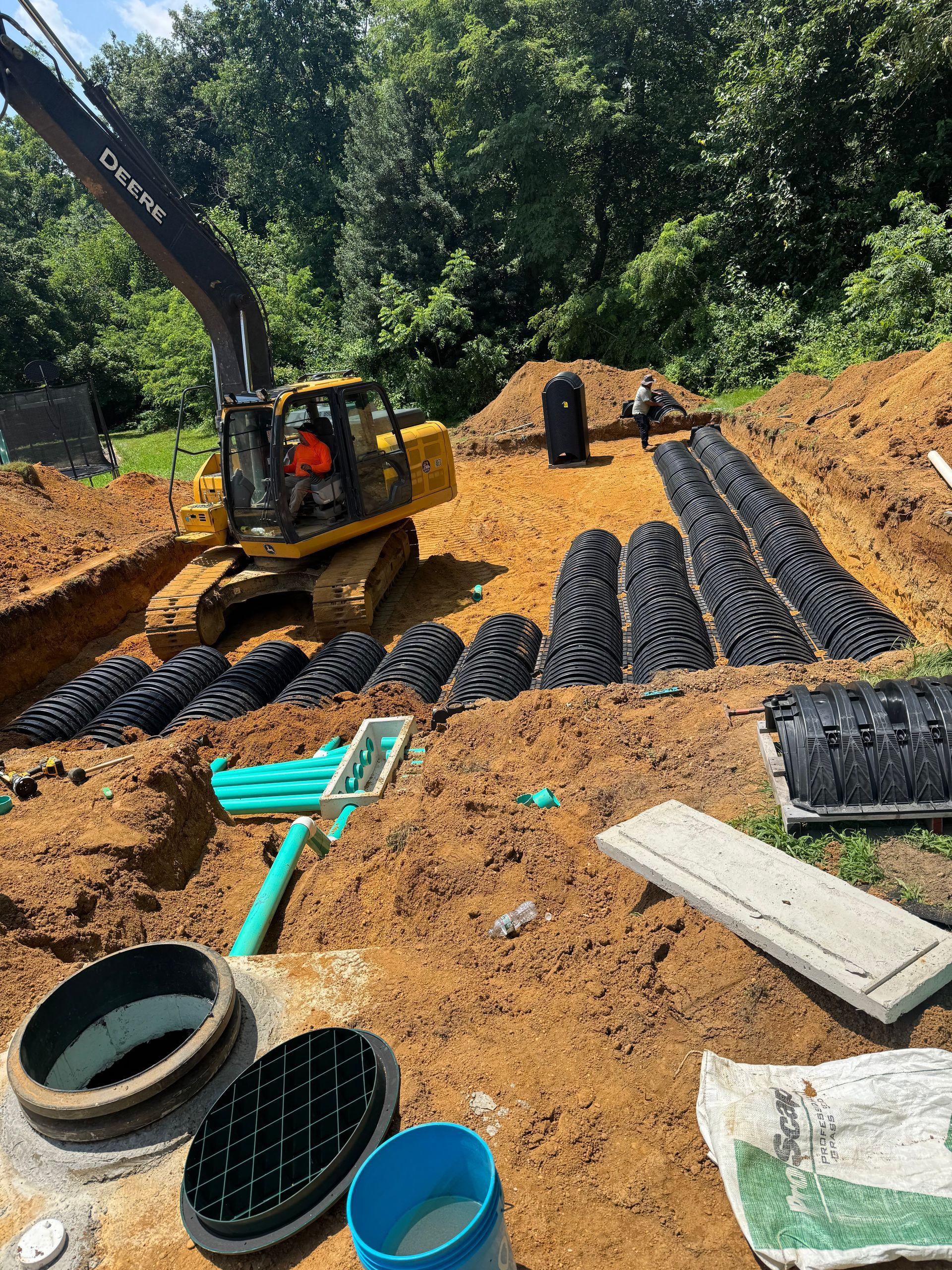 Excavator at a construction site with septic system components.