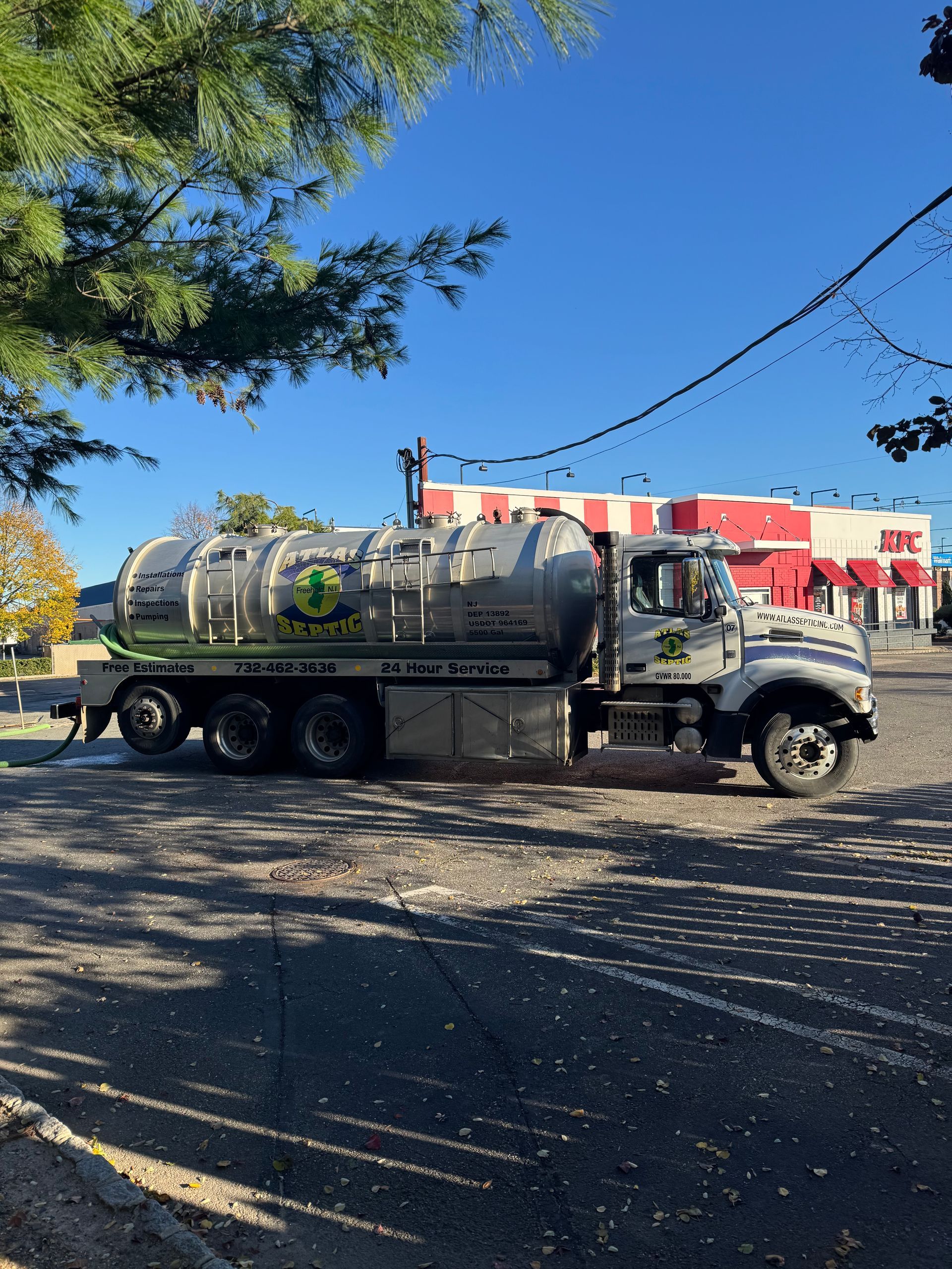 Septic tank truck parked outside a building on a sunny day.