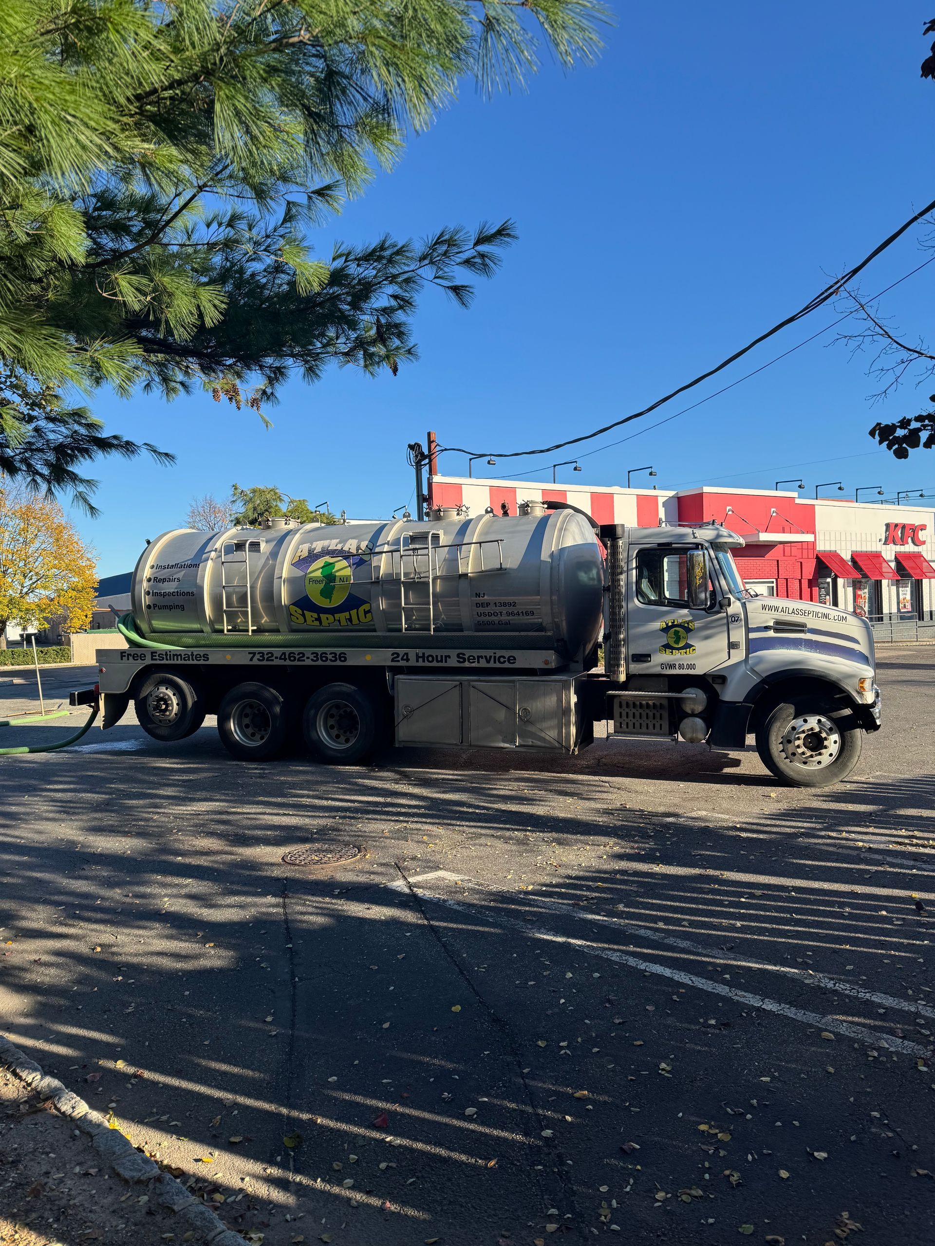 Septic tank truck parked outside a building on a sunny day.