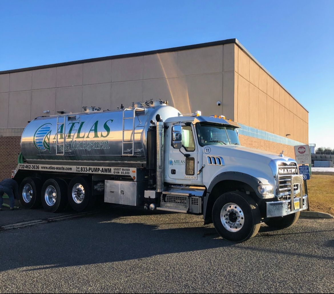 Atlas Environmental Services tanker truck parked in front of a building.