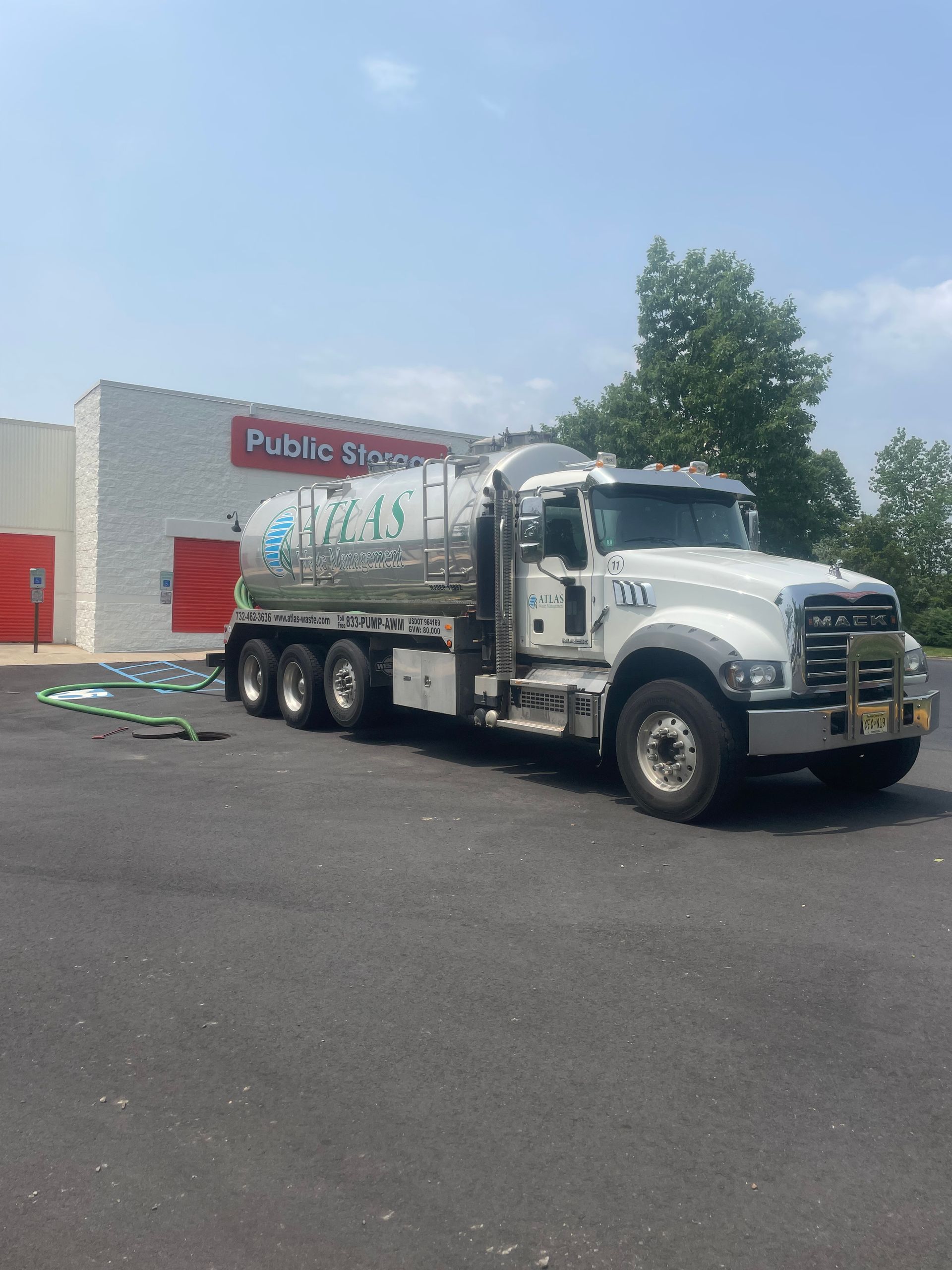 A white tanker truck parked in front of a Public Storage building on a sunny day.