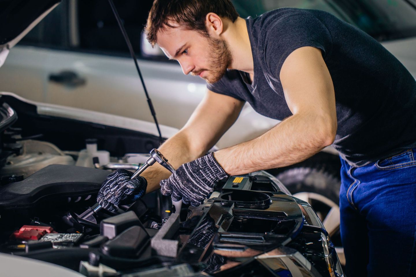 Auto specialist inspecting a car engine under the hood.