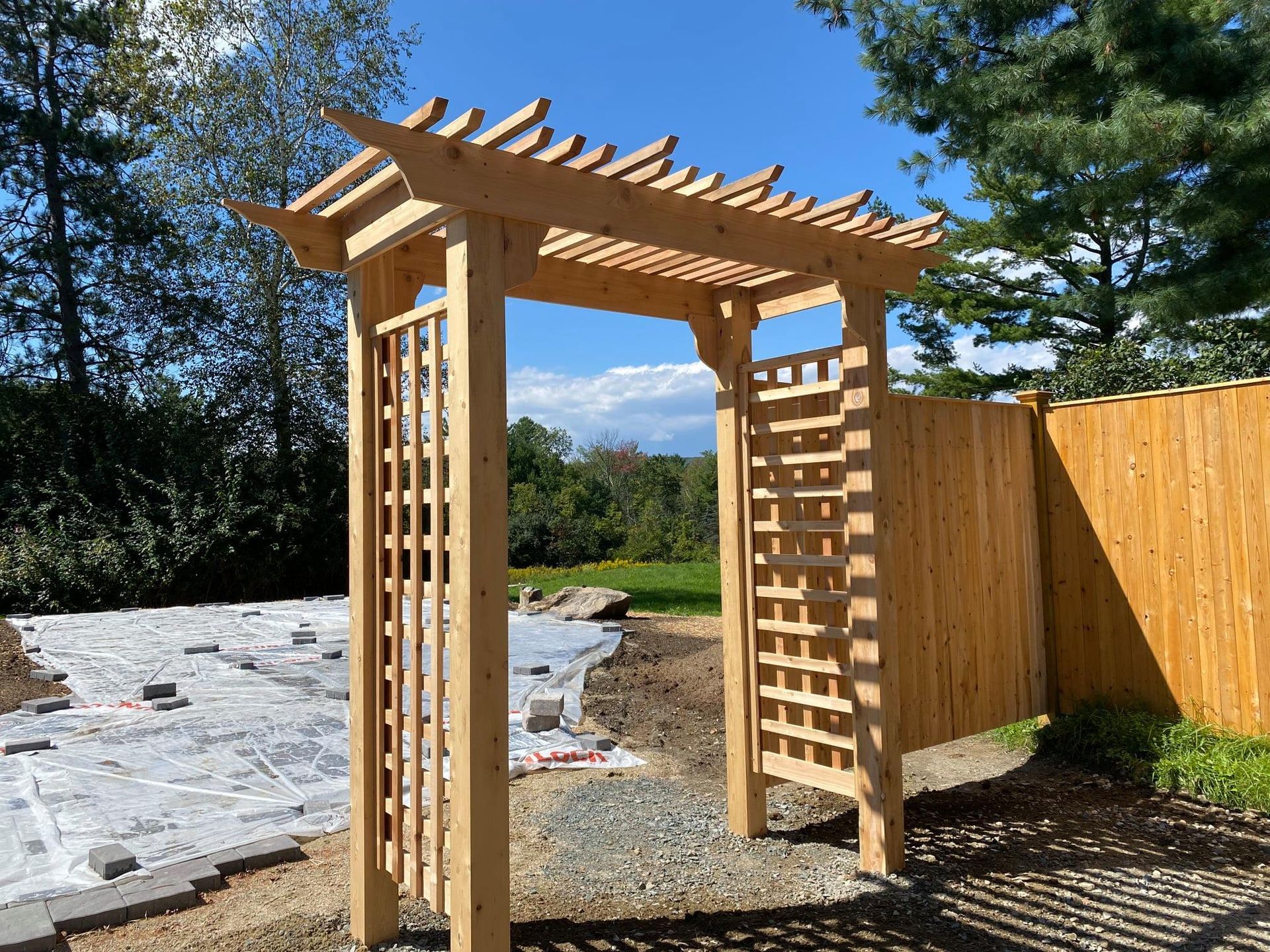 Wooden arbor entrance to a garden with lattice sides and top slats.