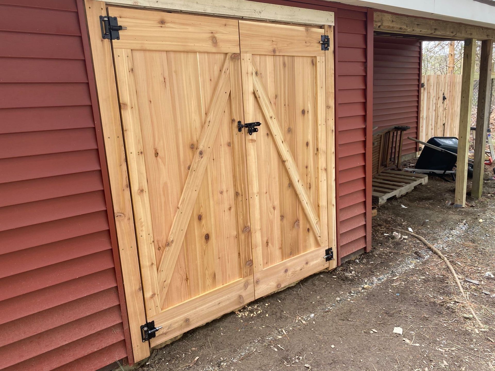 Wooden barn doors on a red shed. Black hardware and an 