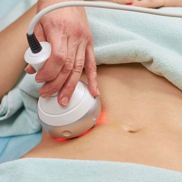 A woman is getting a skin tightening treatment on her stomach.