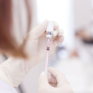 A close up of a person holding a syringe and a bottle.