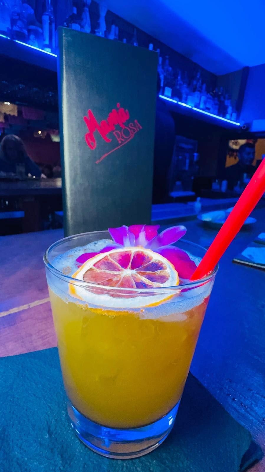 A delicious drink in a glass with a straw, a slice of lemon, and a flower in it